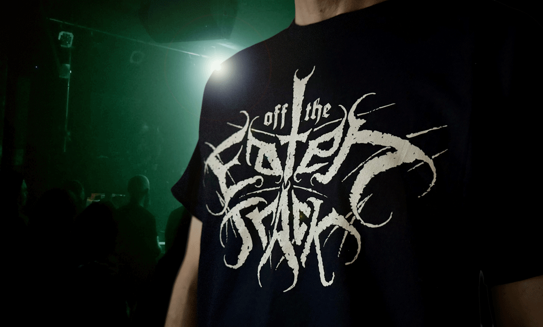 Off the Eaten Track metal-style logo on a black t-shirt under stage lights.